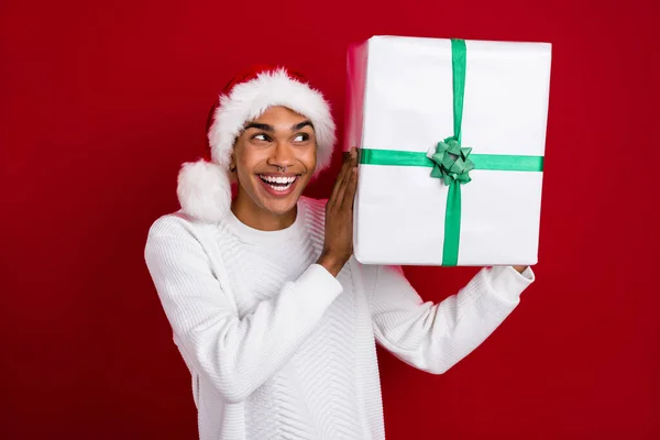 ファンキーなサンタクラスの興奮した男の写真白いプルオーバーを身に着けている白いプルオーバーは 明るい赤の色の背景に隔離された何を推測揺れクリスマスギフト — ストック写真