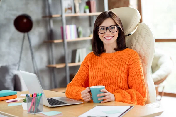 照片上积极迷人的女经理坐在椅子上手握热茶杯享受办公室日常室内生活 — 图库照片