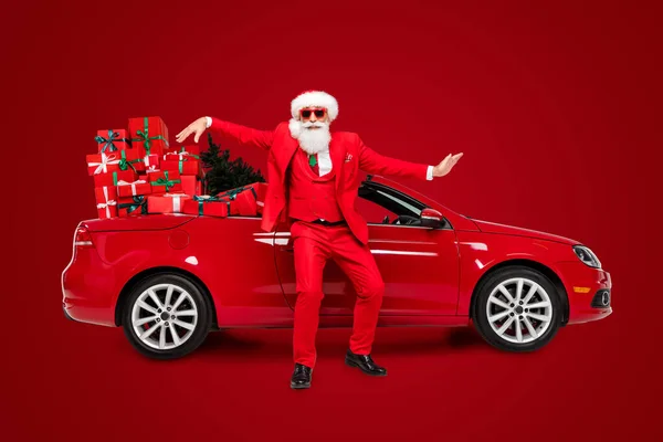 全长体形吸引人的滑稽圣诞老人在汽车前夜在灰色背景的隔离下嬉戏 — 图库照片