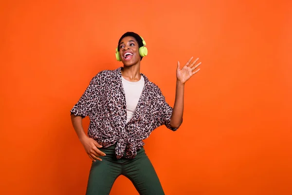 Photo of excited cheerful person have fun enjoy new favorite single song isolated on orange color background.