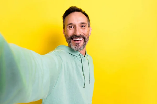 良い気分の肖像画満足快適なハンサムな男服を着た緑パーカー作り自画撮りホールドカメラ孤立した黄色の色の背景 — ストック写真