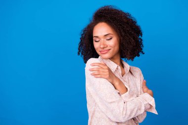 Photo of adorable pretty girl dressed pink blouse closed eyes embracing herself empty space isolated blue color background. clipart