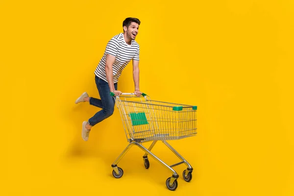 全长图片 滑稽快乐的家伙穿着条纹T恤衫购物超市跳跃高度孤立的黄色背景 — 图库照片