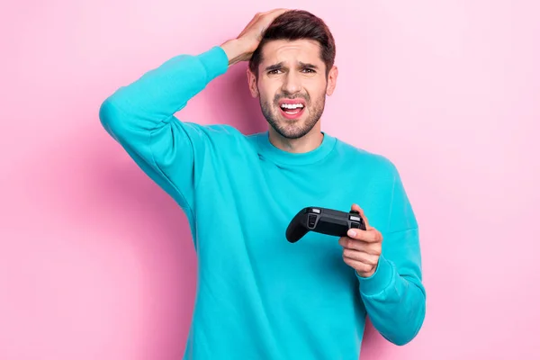 ハンサムな若い男の写真の肖像画はジョイスティックのビデオゲームを保持悩まされたゲーマーはピンクの色の背景に隔離された流行の青い服を着る — ストック写真