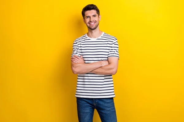 Photo of positive nice young man beaming smile folded arms isolated on yellow color background.
