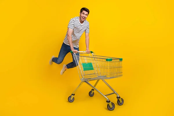 全长照片给人印象深刻的时髦男人穿着白色T恤衫跳高步行超市篮孤立的黄色背景 — 图库照片