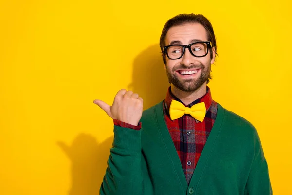 Photo portrait of young nice guy spectacles look curious point empty space wear trendy green look isolated on yellow color background.