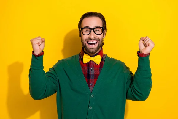 Photo portrait of young nice guy spectacles palm raise fists excited lottery wear trendy green outfit isolated on yellow color background.