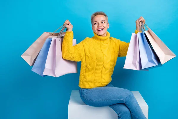 正の喜びの女性の写真は トレンディーな黄色のニットセーターを着用空のスペースは青の色の背景に隔離された店のブランドから多くのバッグを保持 — ストック写真