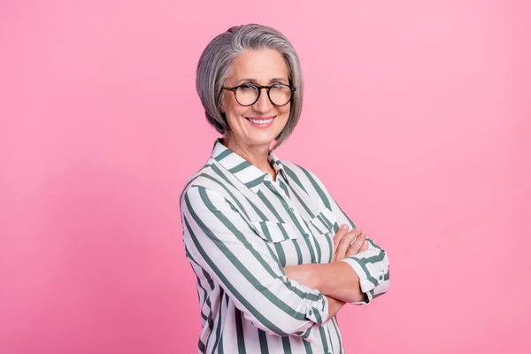 古い引退したビジネス女性の肖像折り畳まれた腕成功した人は眼鏡ストライプシャツを身に着けています彼女のブランドはピンクの色の背景に隔離された楽しむ — ストック写真