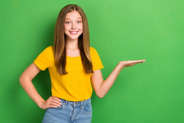 写真のかわいい歯のビーム笑顔ティーン年齢の女の子は黄色のTシャツホールドヤシの木は緑の色の背景に隔離された新しい安価な製品の販売を実証 — ストック写真