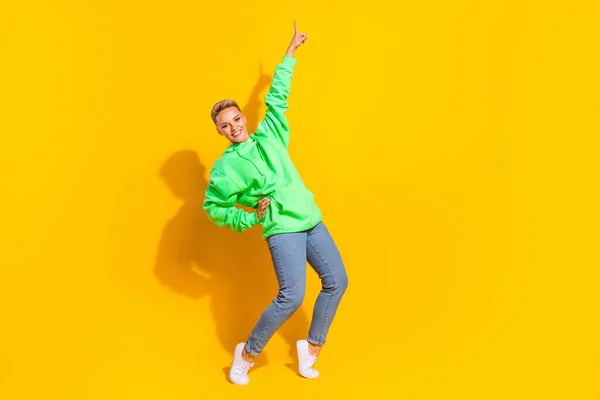 Full length size photo of young funky popular celebrity hipster lady touch hand waist finger point up tiptoes isolated on yellow color background.