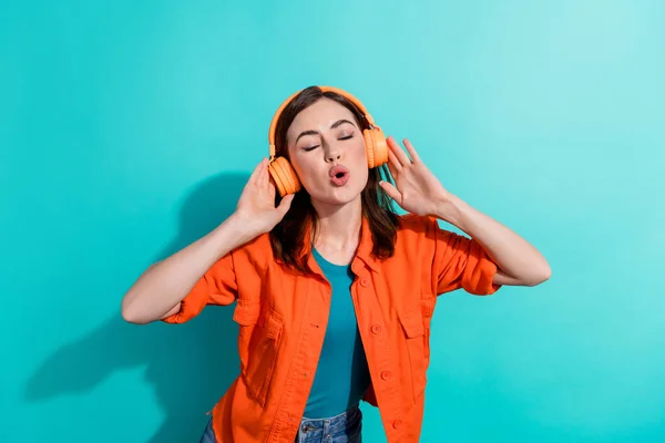 Photo of pretty glad lady eyes closed wear stylish orange outfit listening playlist favorite songs isolated on cyan color background.