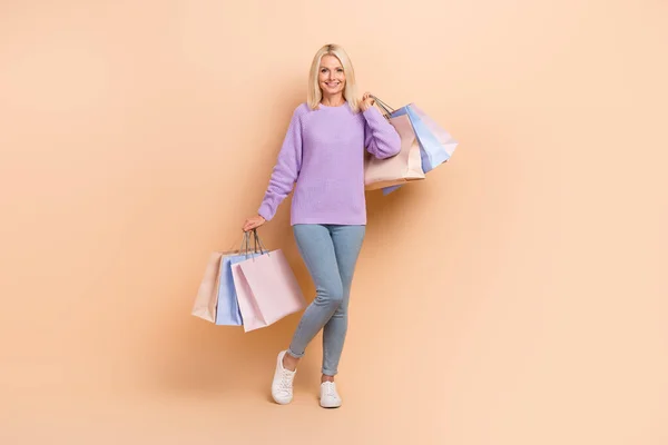 Full length portrait of lovely positive person hands hold bags shopping proposition isolated on beige color background.