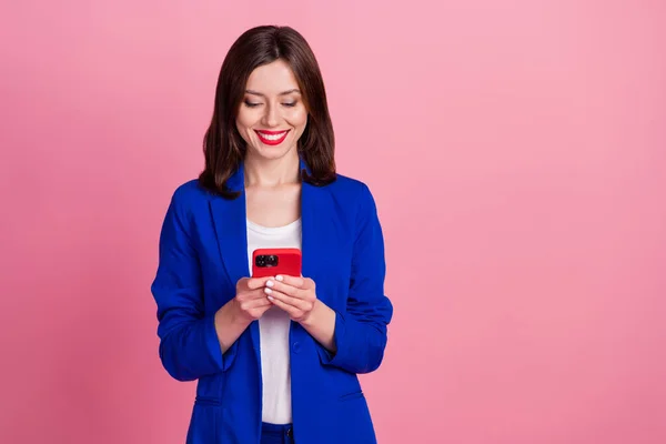 Photo of cheerful lady user wear blue stylish clothes hold telephone read news write post empty space isolated on pink color background.
