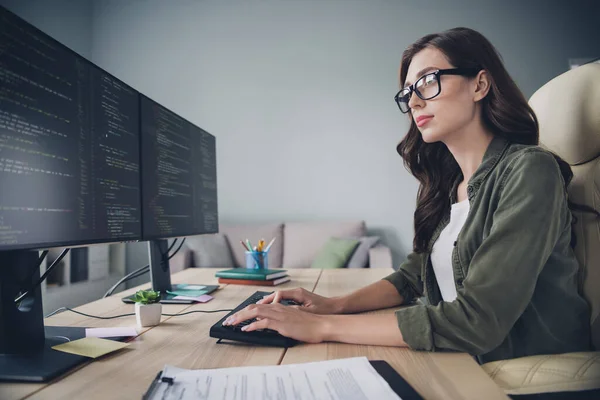 Profile side photo of confident clever lady wear glasses browsing display search bugs mistakes write edits indoor workstation.