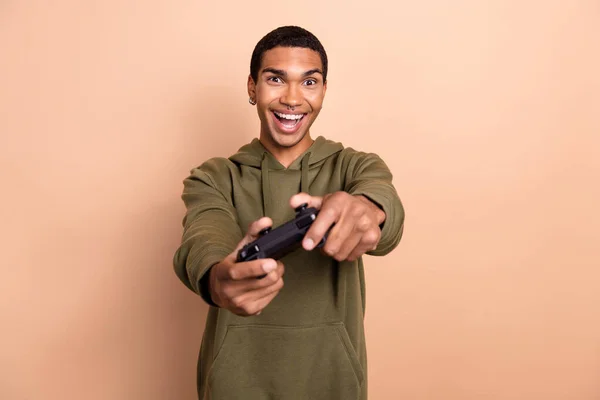 照片显示 积极的男人穿着卡其色时髦的衣服待在家里玩与米色背景隔离的电子游戏 — 图库照片