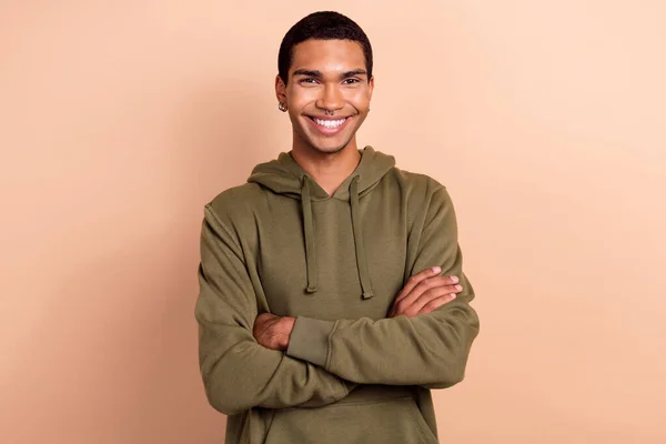 Photo of cute confident guy dressed green khaki hoodie smiling arms crossed isolated beige color background.