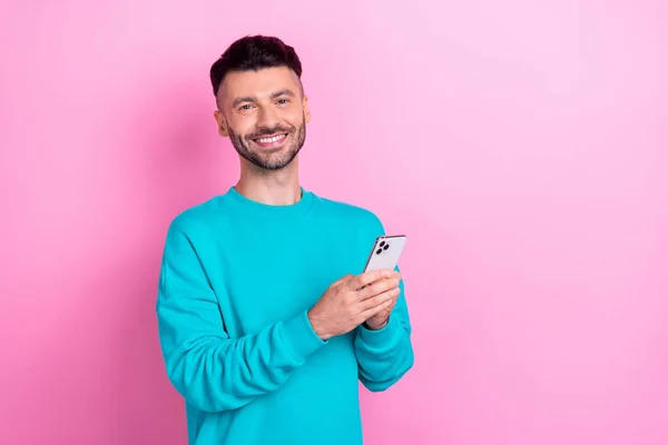 照片上的男人面带微笑地拿着电话 用粉红色背景隔开空旷的空间 — 图库照片