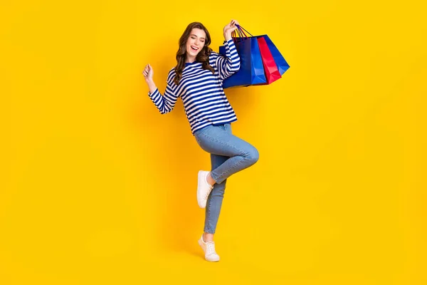 魅力的な若い女性のフルサイズの写真巨大な販売を上げるショッピングバッグを身に着けているスタイリッシュな縞模様の外観黄色の背景に隔離 — ストック写真