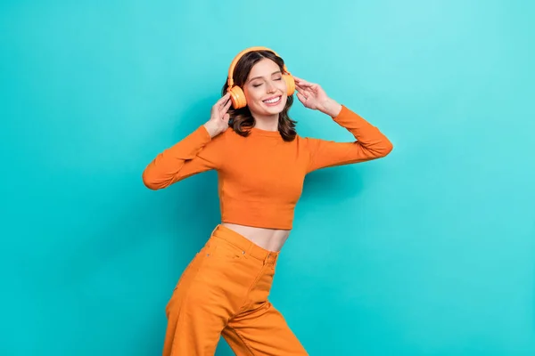 Photo of glad lovely lady wear stylish orange outfit listen favorite hits isolated on cyan color background.