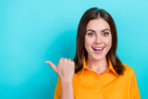 Photo of charming excited lady wear orange shirt showing thumb empty space isolated turquoise color background.