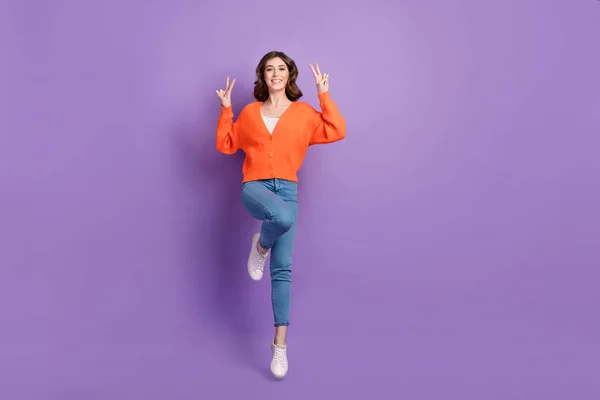 興奮フレンドリーな女性の完全な長さの写真は オレンジカーディガンジャンプ高い示すVサイン隔離された紫色の背景 — ストック写真