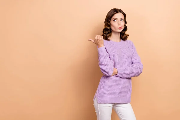 Photo of minded lady wear purple stylish clothes suspicious look empty space offer thinking buy or not isolated on beige color background.