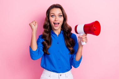 Photo of impressed ecstatic woman with curly hairdo dressed blue blouse hold megaphone clench fist isolated on pink color background. clipart