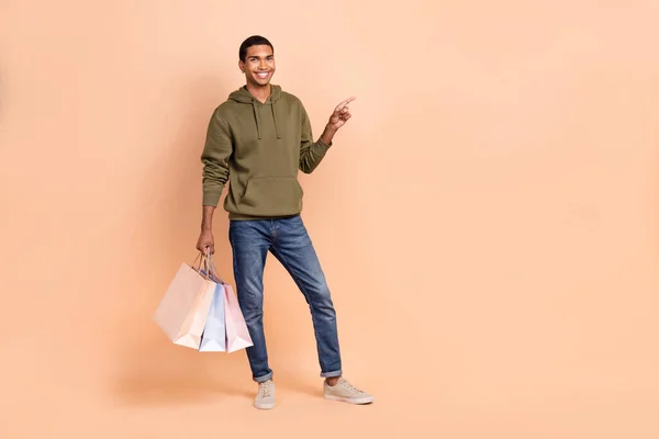 Full length photo of positive man wear stylish denim khaki outfit presenting empty space cool offer deal isolated on beige color background.