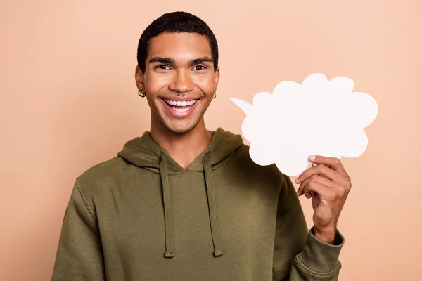 明るい笑顔の男の写真は カーキ色のスウェットシャツを保持紙の雲はベージュの色の背景に隔離された新しい情報フレーズを発表 — ストック写真