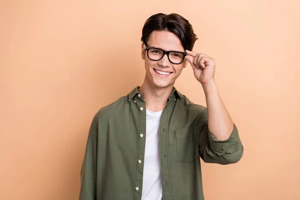 Portrait of satisfied nice person beaming smile hand touch glasses isolated on beige color background.