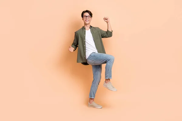 Full body length photo of young overjoyed energetic man wear casual outfit fists up fan support his favorite team isolated on beige color background.