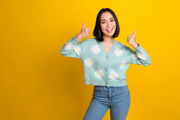 Photo of excited optimistic chinese smile good mood lady wear blue flower print jumper likes thumbs recommend ad isolated on yellow color background.