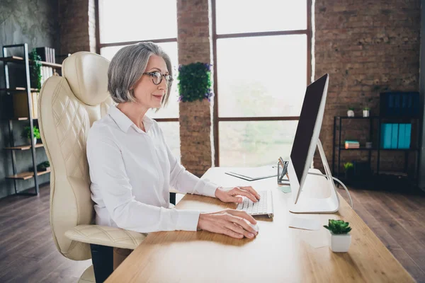 巧妙な経験豊富な経済学者の女性のプロフィール写真革の椅子に座ってキーボード書き込みメッセージメール広々とした職場室内 — ストック写真