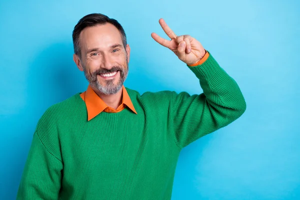 Portrait of satisfied excited person beaming smile hand fingers demonstrate v-sign isolated on blue color background.