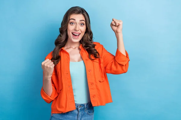 Photo of adorable nice pretty cute woman brunette curly hair raise fists up celebrate her approvement job isolated on blue color background.
