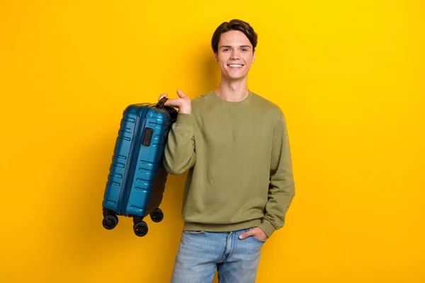 Photo of cheerful nice young man arm hold suitcase toothy smile isolated on yellow color background.
