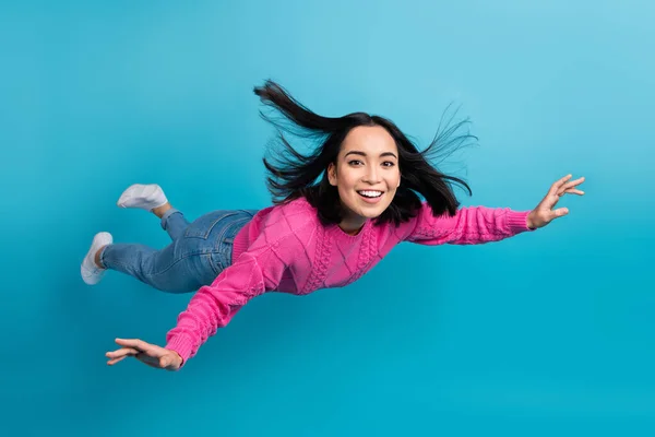 Full length photo of carefree adorable lady wear pink pullover arms wings flying air isolated blue color background.
