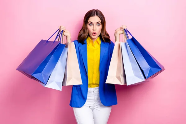 Photo of astonished impressed stunning lady hold many packs spend salary renew wardrobe clothes isolated on pink color background.