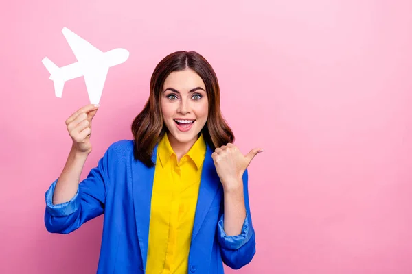 Photo of funny shocked person hand hold little paper plane indicate finger empty space isolated on pink color background.