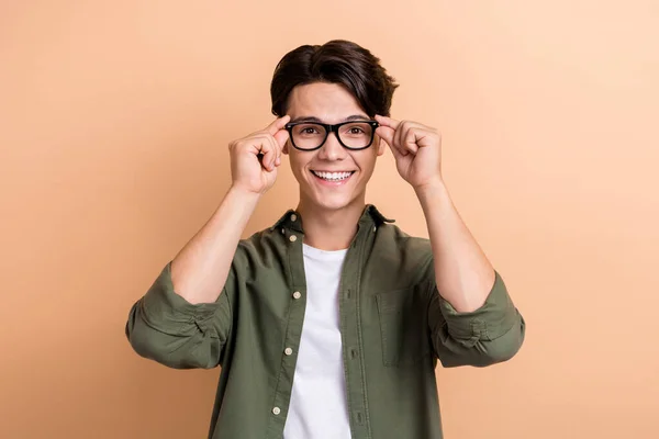 Portrait of positive funny person hands touch eyeglasses beaming smile isolated on beige color background.