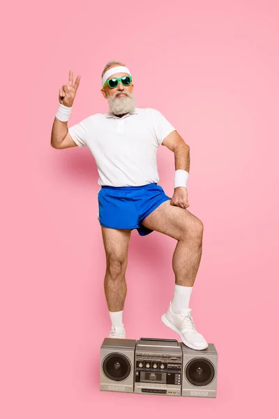 Crazy aged serious athlete pensioner grandpa in eyewear, sneakers, sexy shorts, with bass clipping ghetto blaster recorder. Old school, swag, fooling around, gym, workout, technology.
