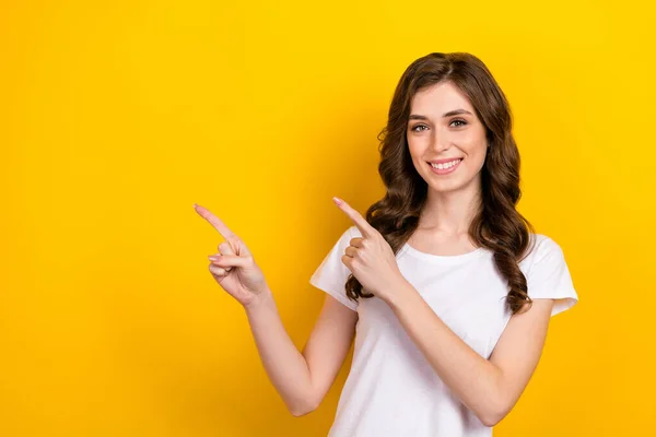 Closeup photo of gorgeous wavy brown hairstyle girl wear white t-shirt smiling directing fingers mockup promotion isolated on yellow color background.