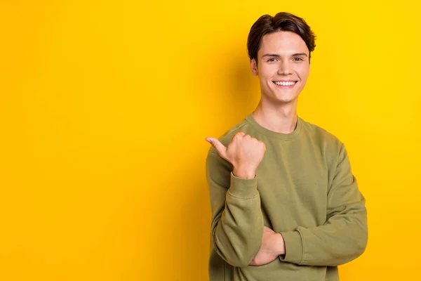 Portrait of cheerful friendly person beaming smile direct thumb finger empty space isolated on yellow color background.