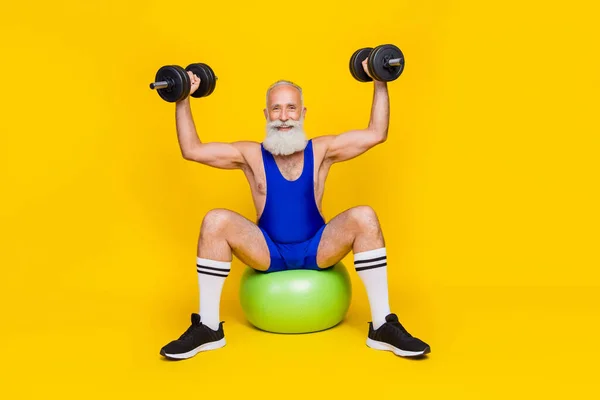 Full body size of pensioner sportsman wear blue costume coach showing for blog exercsie barbell arms up positive isolated on yellow color background.