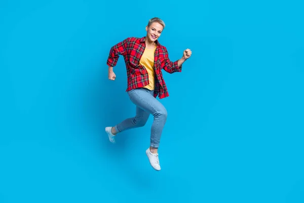 Full length photo of active pleasant good mood woman wear checkered shirt jeans running rush on sale isolated on blue color background.