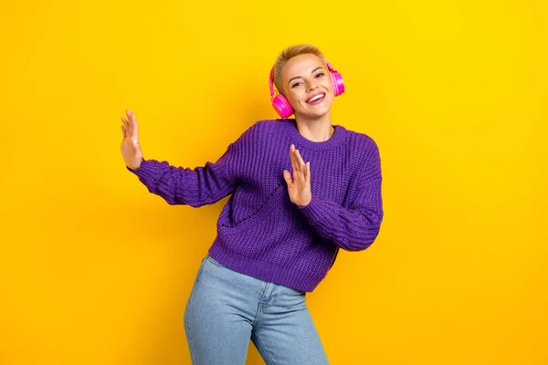Photo of overjoyed lovely lady wear stylish violet clothes enjoy new quality earbuds have fun isolated on yellow color background.