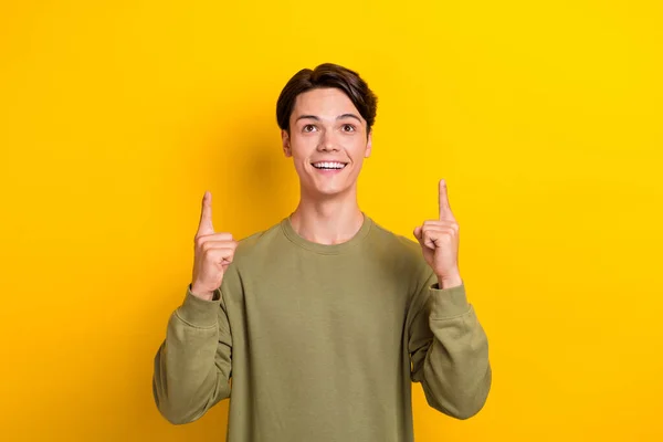 Photo of nice positive person look direct fingers empty space isolated on yellow background.