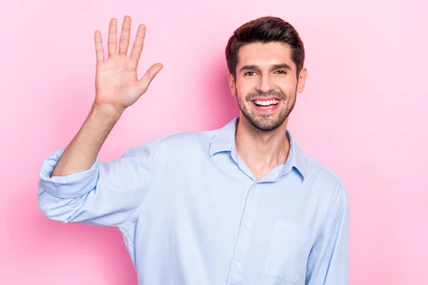 Photo of optimistic positive man waving hand palm meet friends colleagues hello symbol isolated on pink color background.